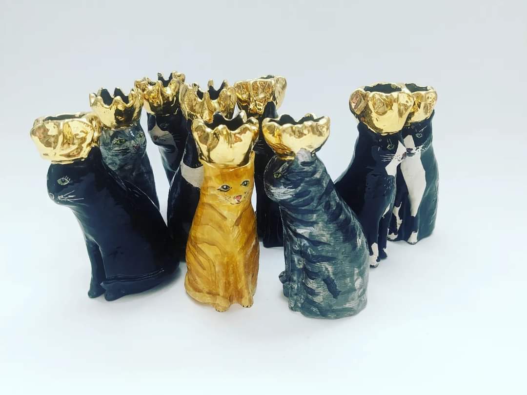 A collection of ceramic cats wearing gold crowns.