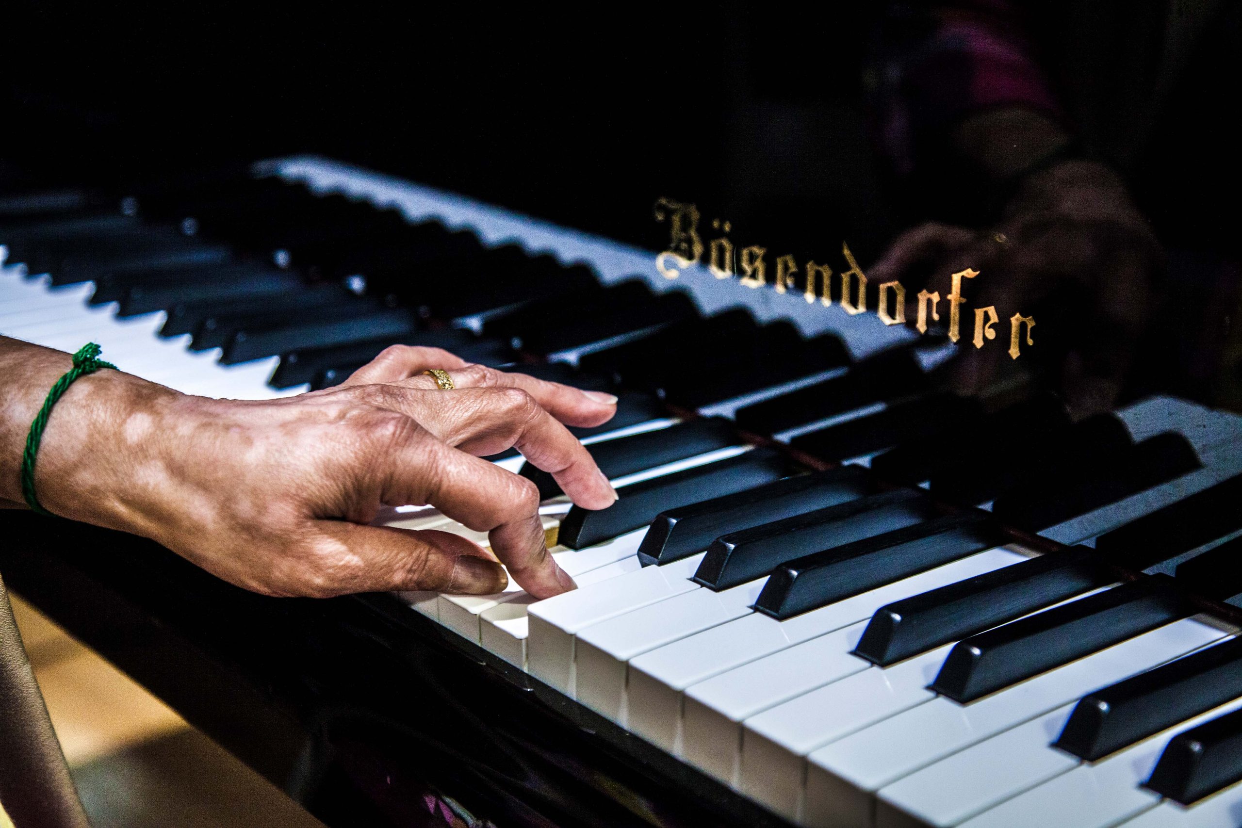 A hand playing the keys of a grand piano.