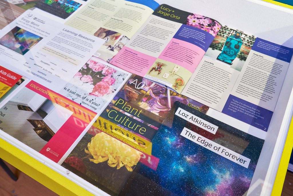 A glass cabinet containing many brochures and leaflets from past exhibitions.