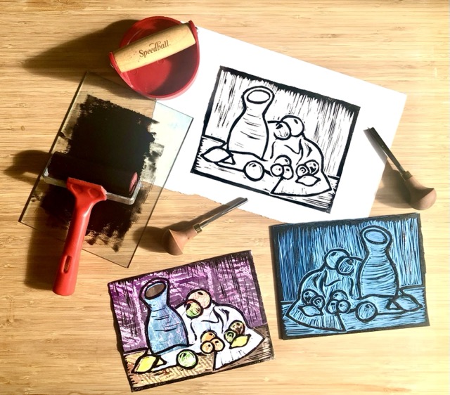 A collection of prints and printmaking material messily on a table.