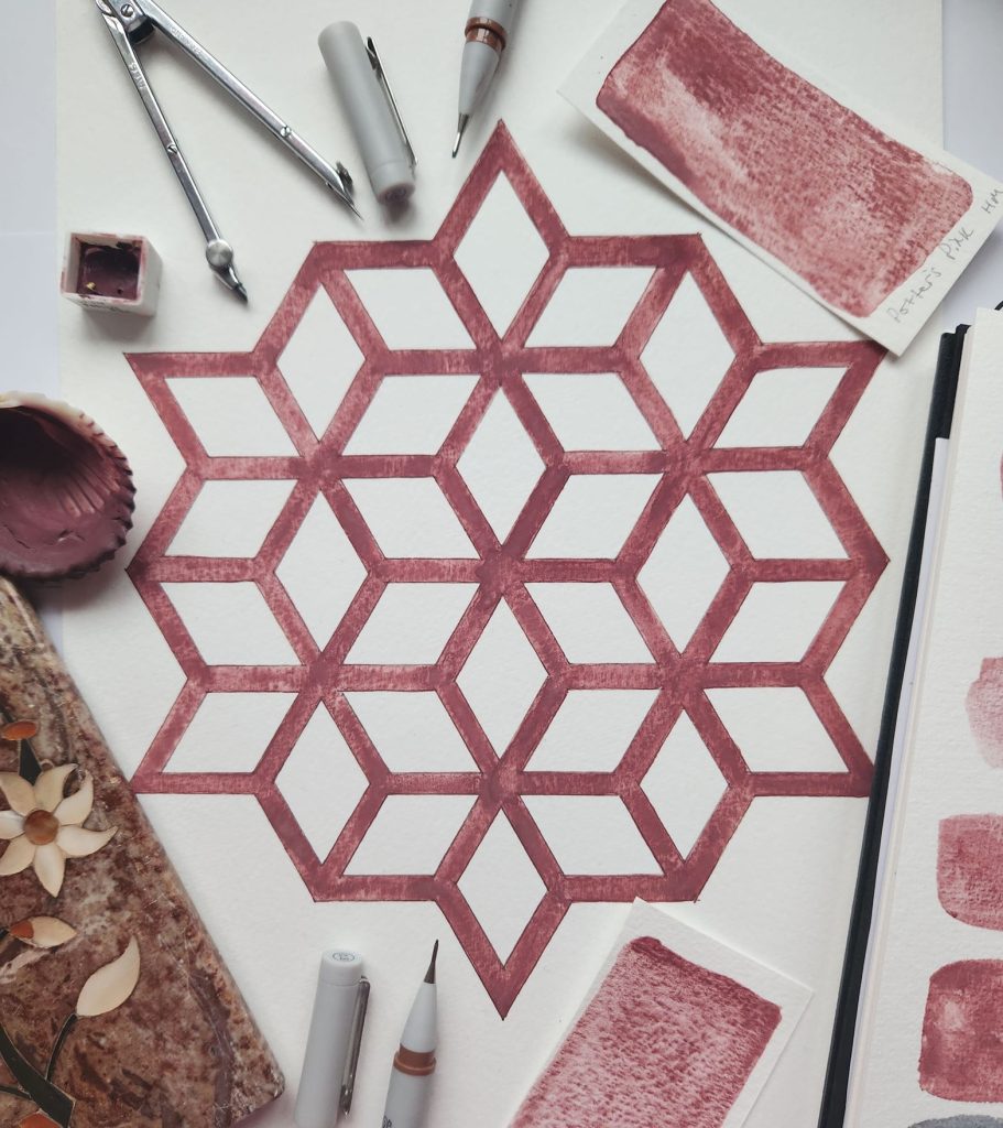 An inked 6-fold Islamic geometry drawn on paper, surrounded by drawing materials.