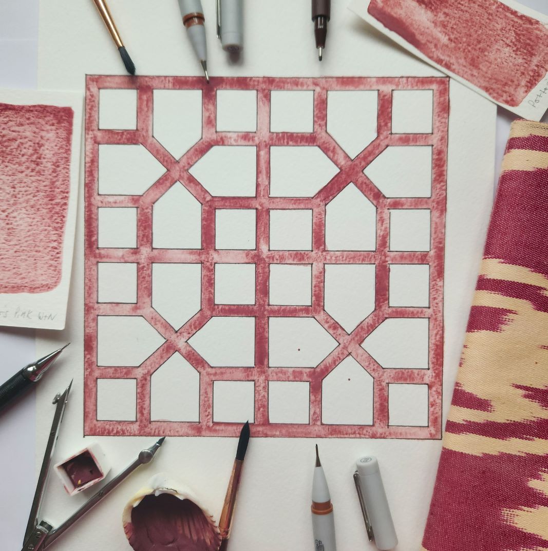 An inked 8-fold Islamic geometry drawn on paper, surrounded by drawing materials.