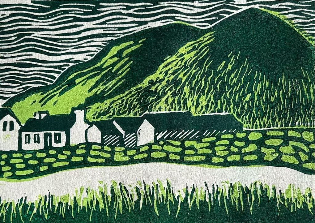 A lino print of a village with a mountain range and river in greens, blacks and white.