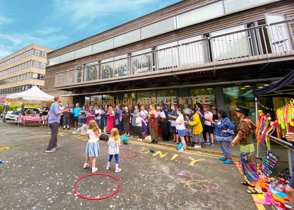 Families outside of Attenborough Arts Centre having a fun party with colourful toys.