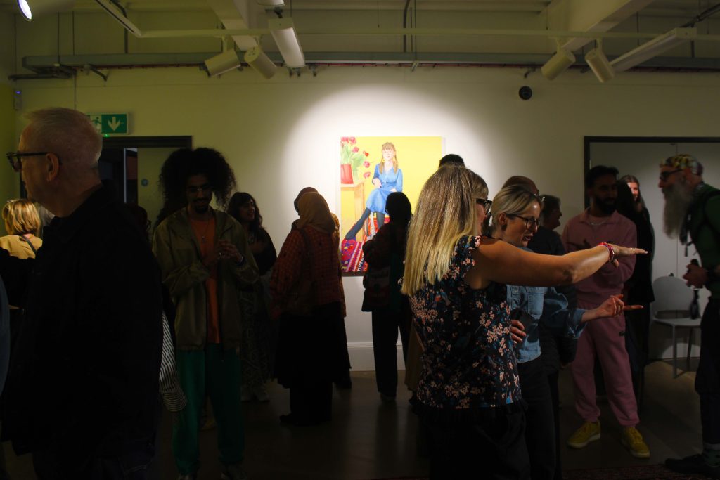 A gallery space full of paper with a highlighted oil painting of a women in a wheelchair on the back wall.
